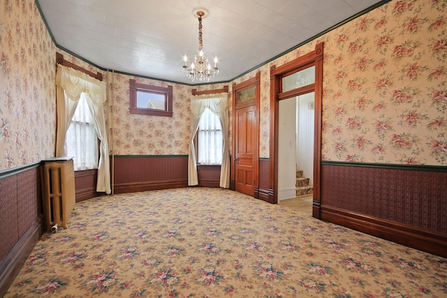 unfurnished room with ornamental molding, carpet floors, and a notable chandelier