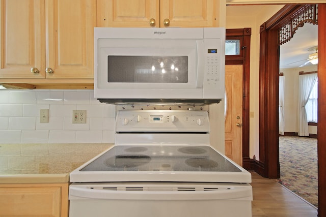 kitchen featuring wood-type flooring, a wealth of natural light, white appliances, and backsplash