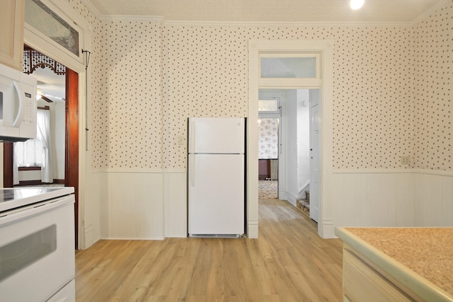 kitchen featuring ornamental molding, a healthy amount of sunlight, light hardwood / wood-style flooring, and white appliances