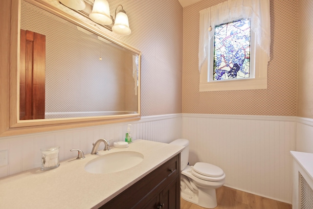 bathroom featuring vanity with extensive cabinet space, toilet, and hardwood / wood-style flooring