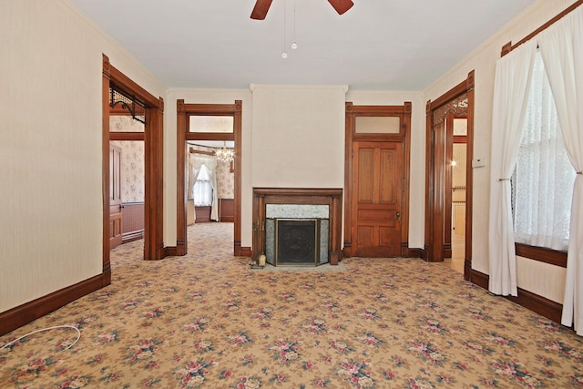 unfurnished living room with a premium fireplace, crown molding, ceiling fan, and carpet floors