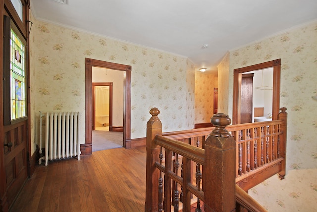 hall with hardwood / wood-style floors, ornamental molding, and radiator heating unit