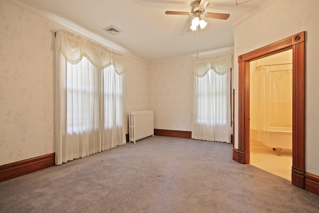 carpeted empty room featuring ornamental molding, ceiling fan, a healthy amount of sunlight, and radiator