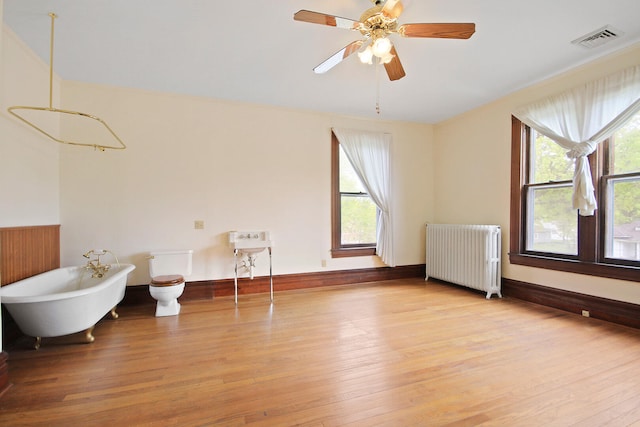 spare room with hardwood / wood-style floors, ceiling fan, and radiator