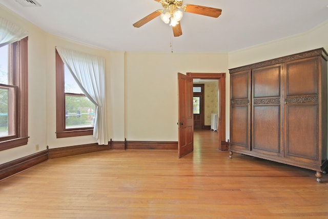 unfurnished bedroom with ornamental molding, light hardwood / wood-style flooring, ceiling fan, and radiator