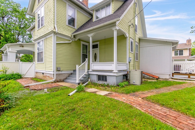 view of front of house featuring central AC unit, a porch, and a front yard