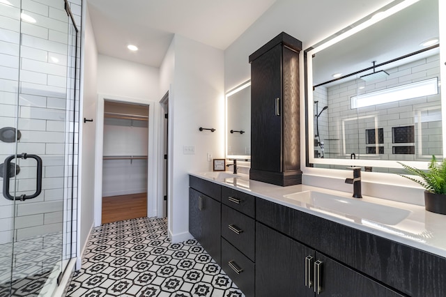 bathroom with a shower with shower door, vanity with extensive cabinet space, dual sinks, and tile floors