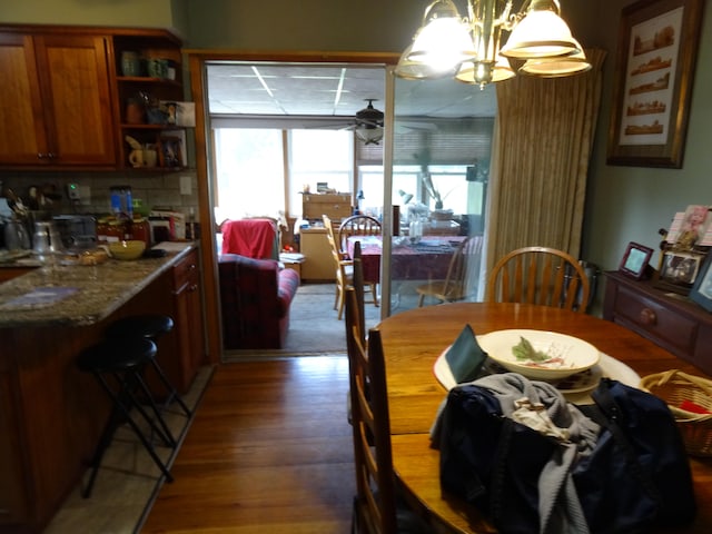 dining area featuring dark hardwood / wood-style floors, plenty of natural light, and ceiling fan with notable chandelier