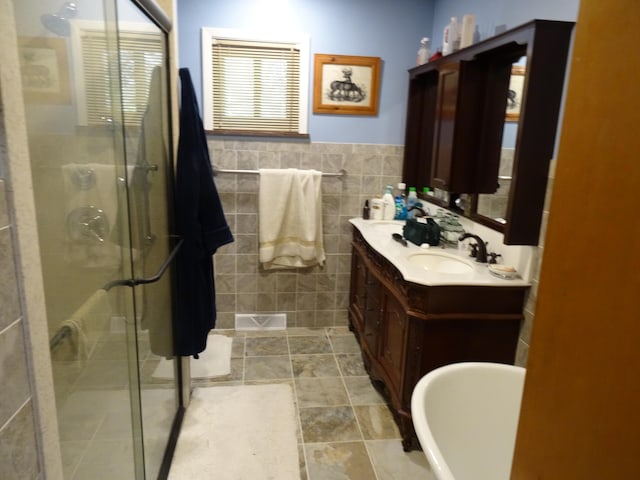 bathroom featuring tile walls, tile flooring, large vanity, and shower with separate bathtub