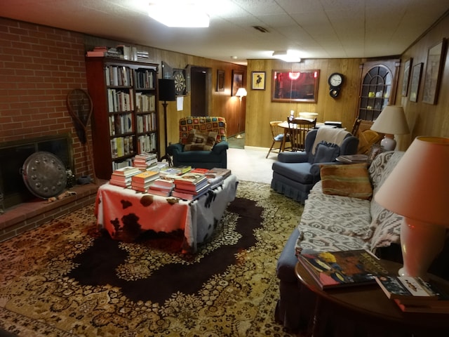 carpeted living room with a brick fireplace and wood walls