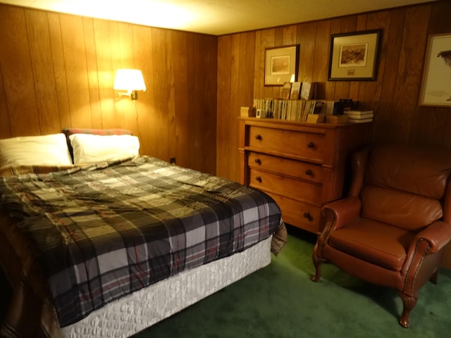 bedroom with dark colored carpet and wood walls