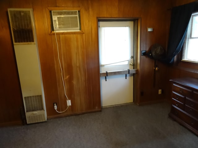 carpeted bedroom featuring wood walls and a wall mounted air conditioner