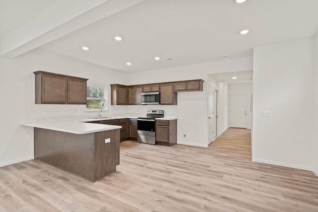 kitchen featuring kitchen peninsula, sink, stainless steel appliances, and light hardwood / wood-style floors