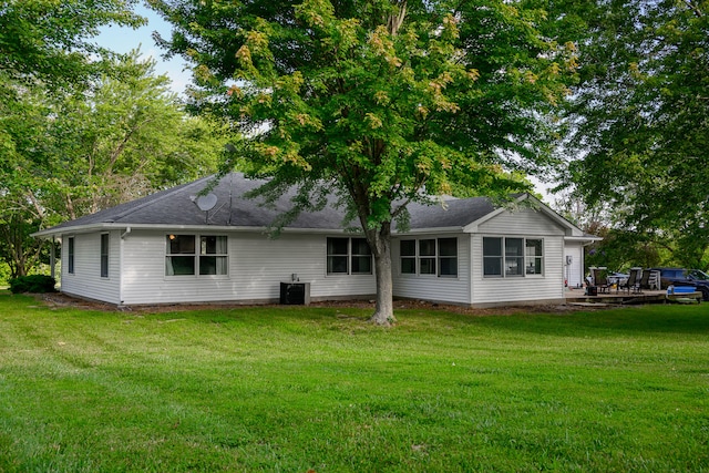 rear view of property with central AC unit and a lawn