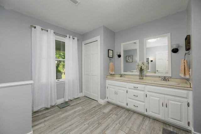 bathroom with double sink, large vanity, and hardwood / wood-style floors