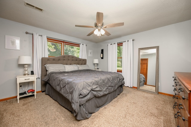 carpeted bedroom featuring ceiling fan and a textured ceiling