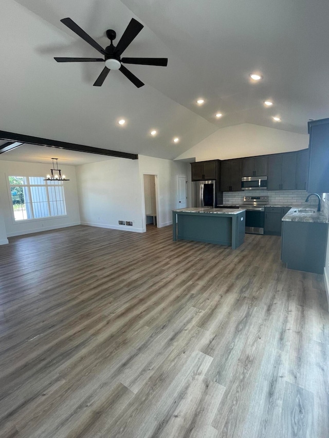 kitchen featuring ceiling fan with notable chandelier, stainless steel appliances, a kitchen island, sink, and decorative backsplash