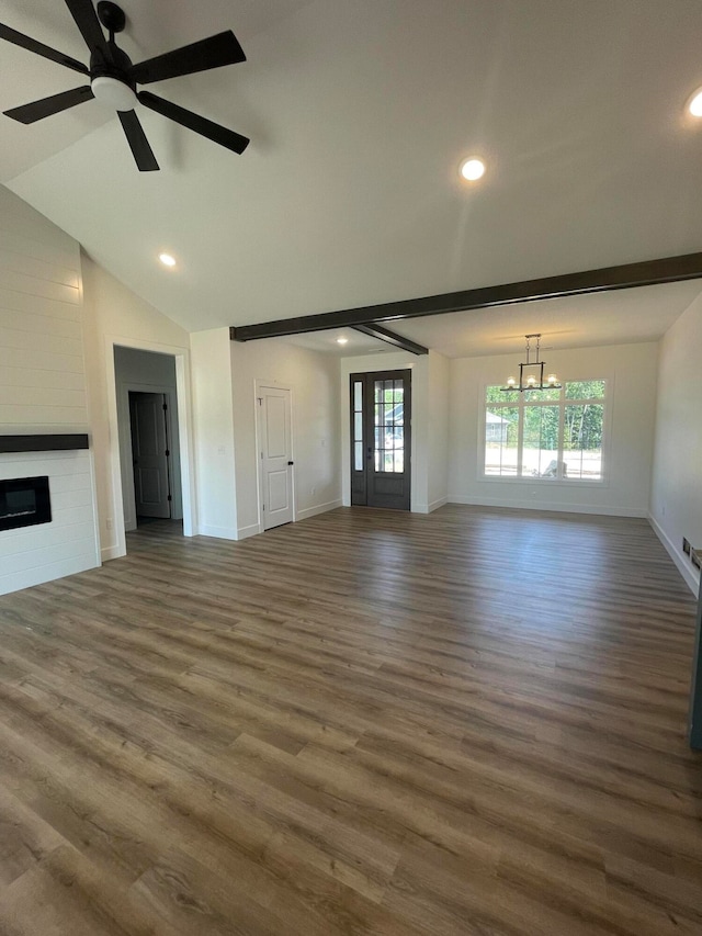 unfurnished living room with ceiling fan with notable chandelier, lofted ceiling, a fireplace, and dark hardwood / wood-style floors