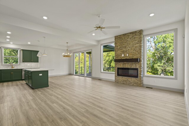 1704 Stillpoint Ct, Columbia, MO 65203 - unfurnished living room with light wood-style flooring, baseboards, a stone fireplace, a sink, and ceiling fan with notable chandelier
