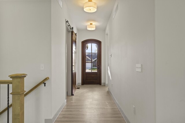 1704 Stillpoint Ct, Columbia, MO 65203 - doorway to outside featuring a barn door, arched walkways, baseboards, and light wood-style floors