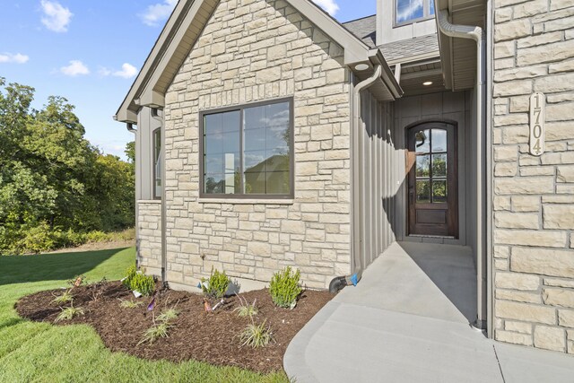 1704 Stillpoint Ct, Columbia, MO 65203 - view of exterior entry with stone siding, board and batten siding, a shingled roof, and a lawn