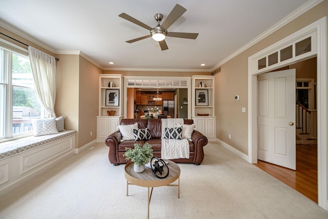 carpeted living room with ceiling fan and ornamental molding