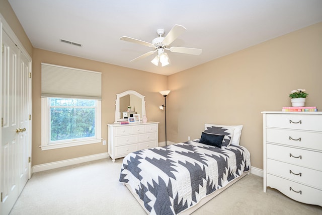 bedroom with ceiling fan, light carpet, and a closet