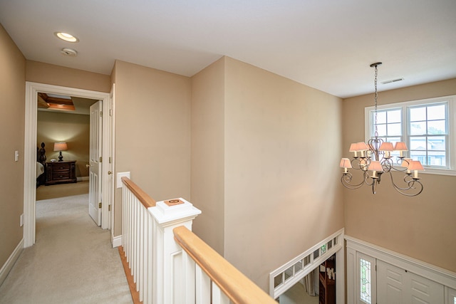 hallway featuring light carpet and an inviting chandelier