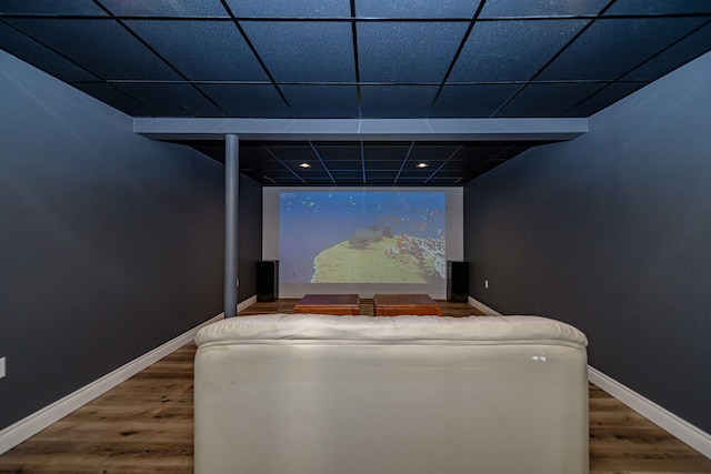 cinema room featuring a paneled ceiling and hardwood / wood-style flooring