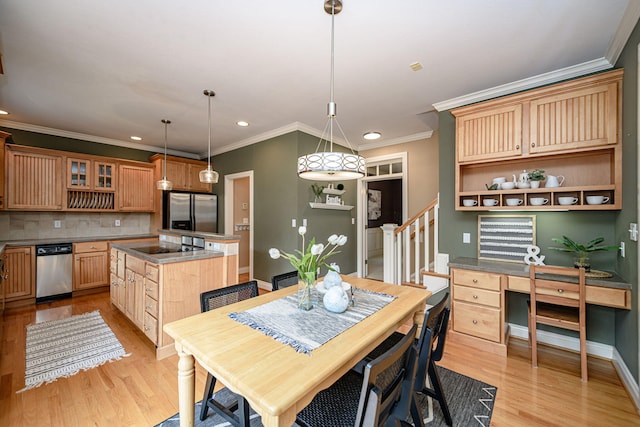 dining space with built in desk, crown molding, and light hardwood / wood-style floors