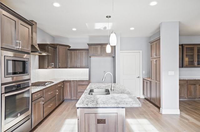 1703 Linkside Dr, Columbia, MO 65201 - kitchen with appliances with stainless steel finishes, a sink, a center island with sink, light wood-style floors, and decorative backsplash