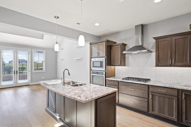 1703 Linkside Dr, Columbia, MO 65201 - kitchen with stainless steel appliances, wall chimney range hood, a sink, backsplash, and light wood-style flooring