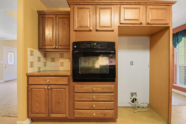 604 Adens Woods Ct, Columbia, MO 65201 - kitchen featuring oven, brown cabinets, tasteful backsplash, light countertops, and light tile patterned floors