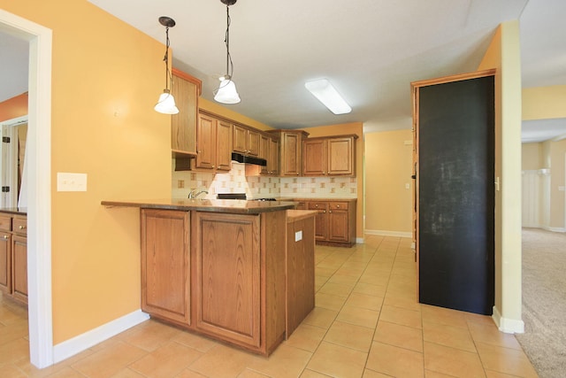 604 Adens Woods Ct, Columbia, MO 65201 - kitchen featuring under cabinet range hood, decorative backsplash, a peninsula, brown cabinetry, and hanging light fixtures