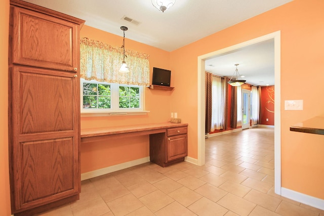604 Adens Woods Ct, Columbia, MO 65201 - kitchen featuring built in study area, light tile patterned flooring, decorative light fixtures, and brown cabinets