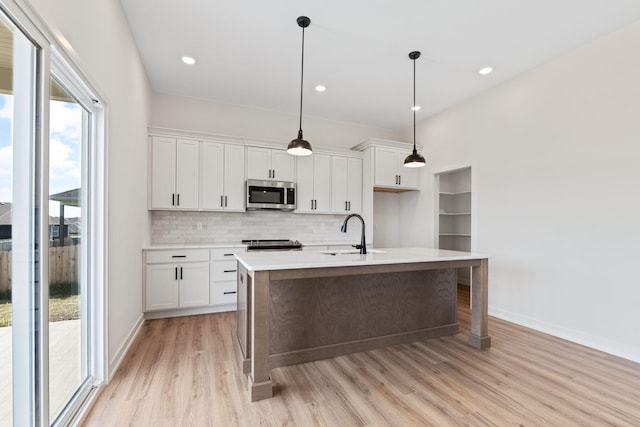 kitchen with appliances with stainless steel finishes, sink, an island with sink, and white cabinets