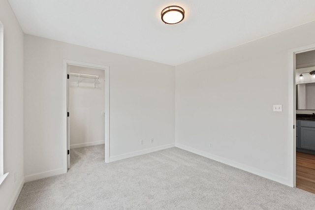 unfurnished bedroom with a spacious closet, a closet, and light carpet