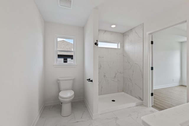 bathroom with a tile shower and toilet