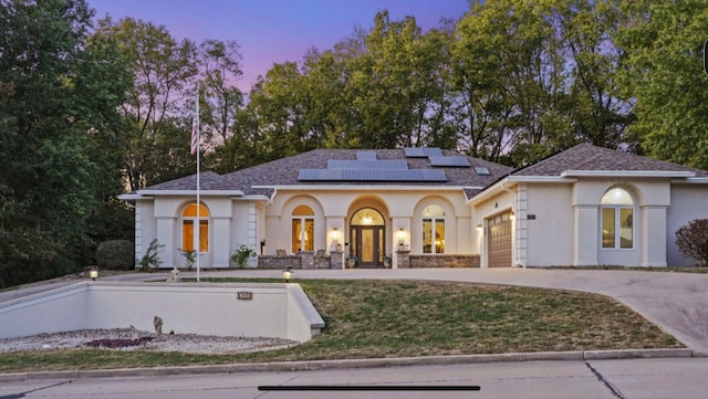 view of front of home with solar panels, a yard, and a garage