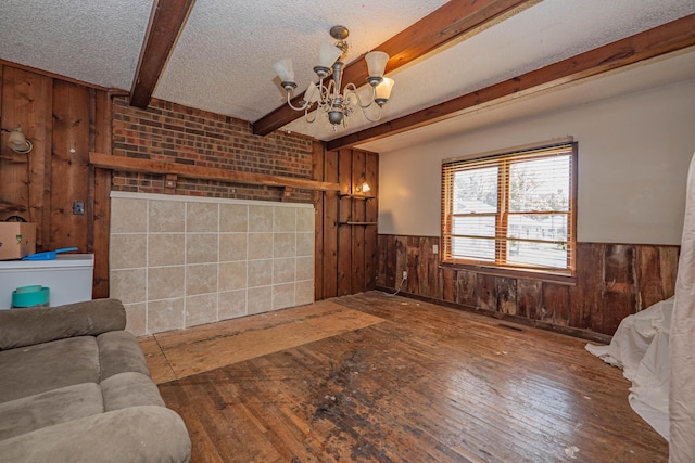 living room featuring beam ceiling, a textured ceiling, hardwood / wood-style flooring, and an inviting chandelier