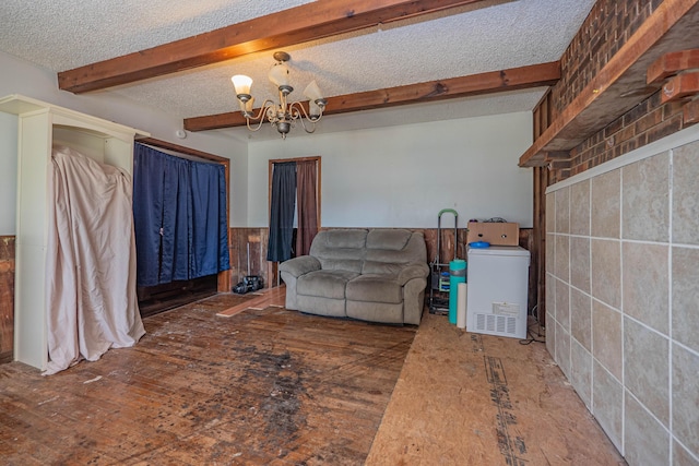 living room featuring beam ceiling, a textured ceiling, washer / clothes dryer, and a notable chandelier