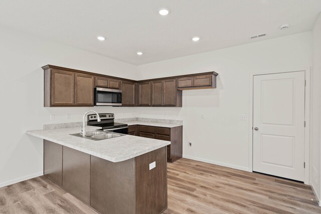 kitchen with sink, stainless steel appliances, kitchen peninsula, light hardwood / wood-style floors, and dark brown cabinets