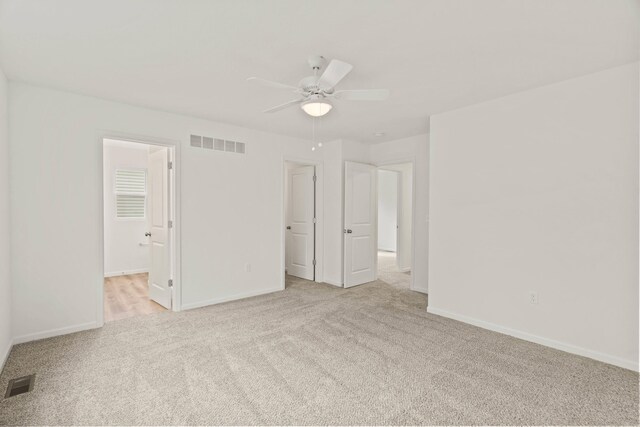 unfurnished bedroom featuring a closet, ceiling fan, ensuite bathroom, and light carpet