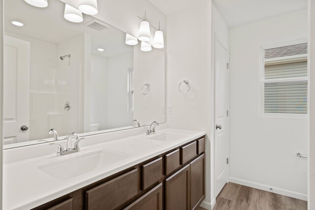 bathroom featuring hardwood / wood-style floors, vanity, toilet, and walk in shower