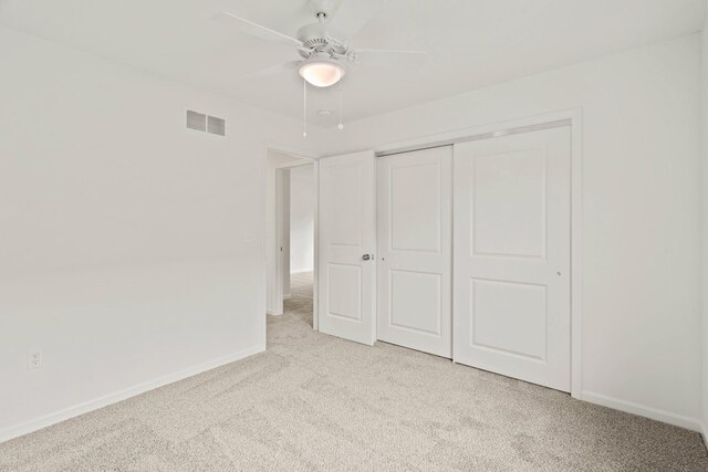 unfurnished bedroom featuring ceiling fan, a closet, and light colored carpet