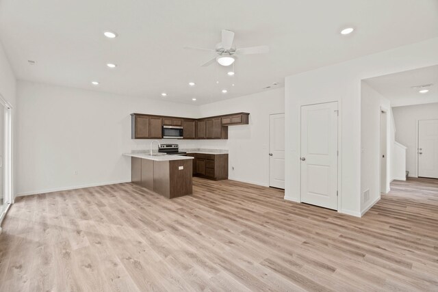 kitchen featuring ceiling fan, sink, light hardwood / wood-style flooring, kitchen peninsula, and appliances with stainless steel finishes