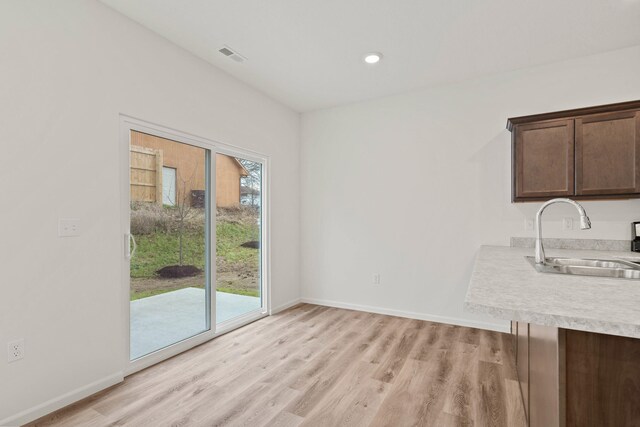 unfurnished dining area with sink and light wood-type flooring