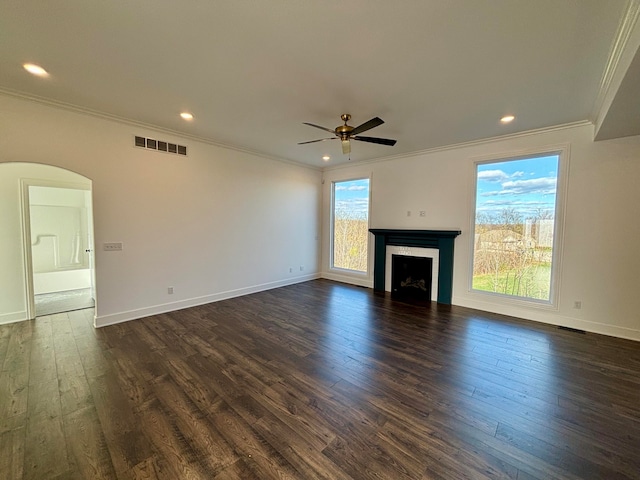 unfurnished living room with arched walkways, dark wood finished floors, a fireplace, visible vents, and ornamental molding