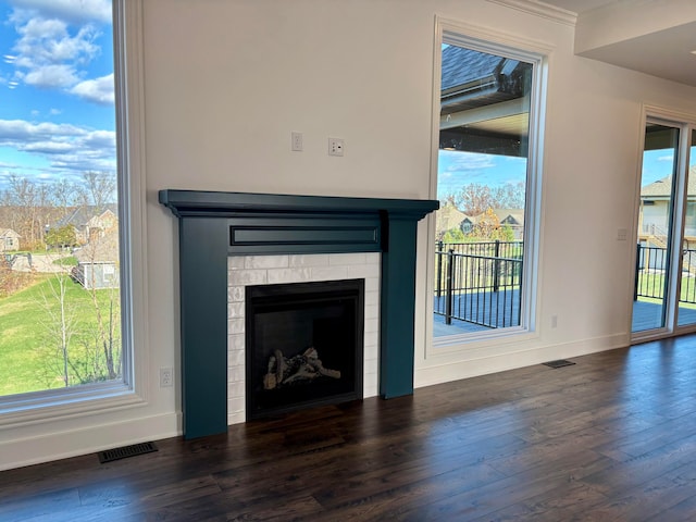 unfurnished living room featuring a healthy amount of sunlight, dark wood-style floors, and visible vents