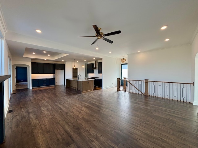 unfurnished living room featuring dark wood-style floors, ornamental molding, a sink, and recessed lighting